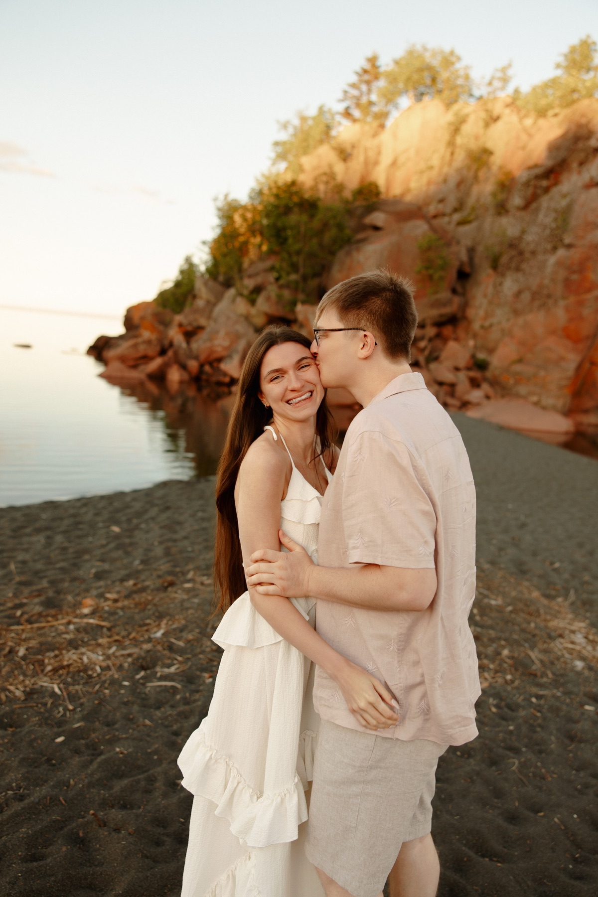 The couple smiling together beside the water